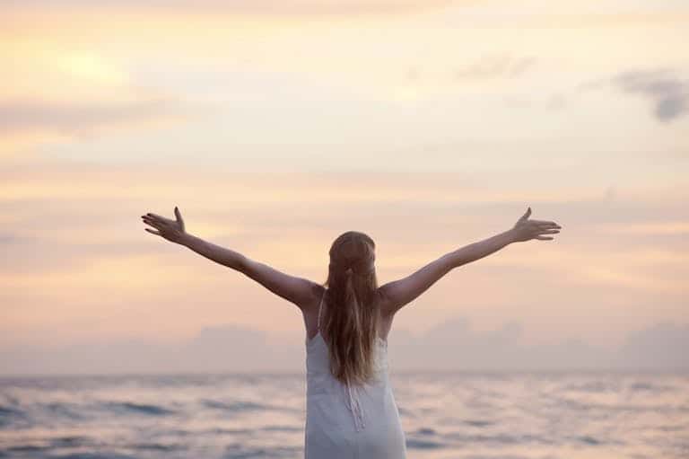 A woman enjoying a serene sunset on Unawatuna Beach, Sri Lanka, depicting boosting your mood and raising your vibration.