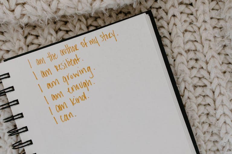 Notebook with handwritten postive affirmations on knitted fabric background.
