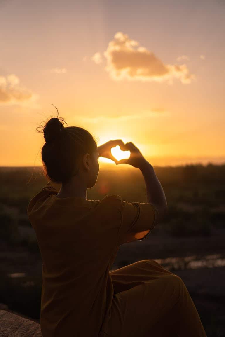 Silhouette of a person forming a heart with hands against a Morocco sunset. To represent self-love.