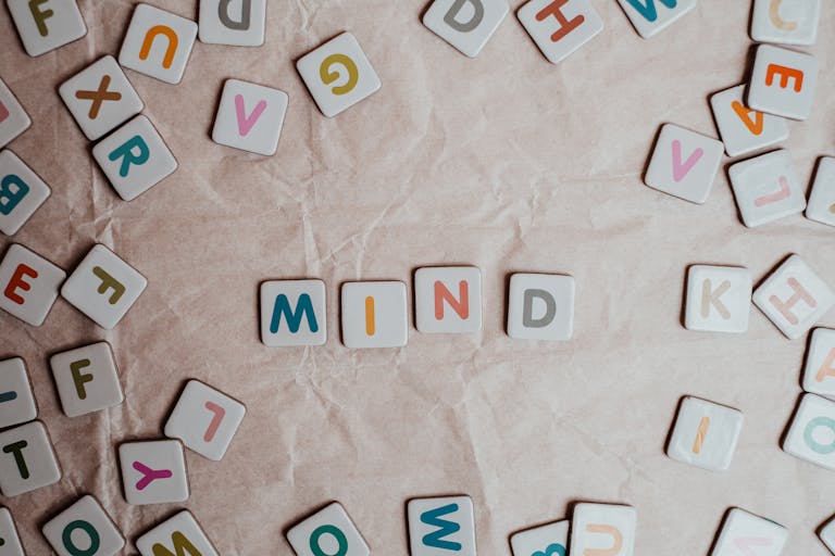 Close-up of scattered letter tiles spelling 'mind' on crumbled paper background to represent subliminals and the subsconsious mind.