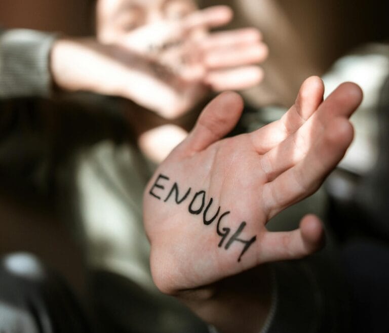 Blurred person with 'Enough' written on palm, expressing that we are good enough.