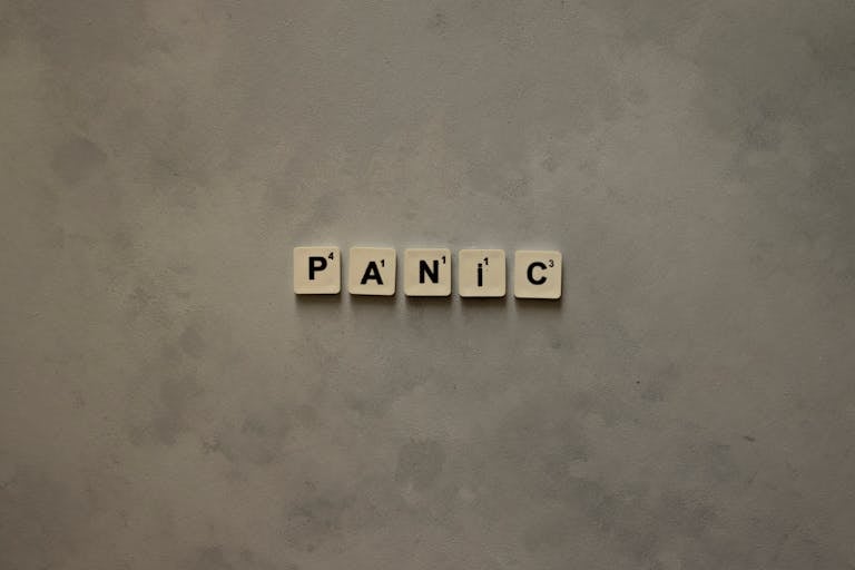 Scrabble tiles forming the word 'Panic' on a simple neutral background, symbolizing anxiety.