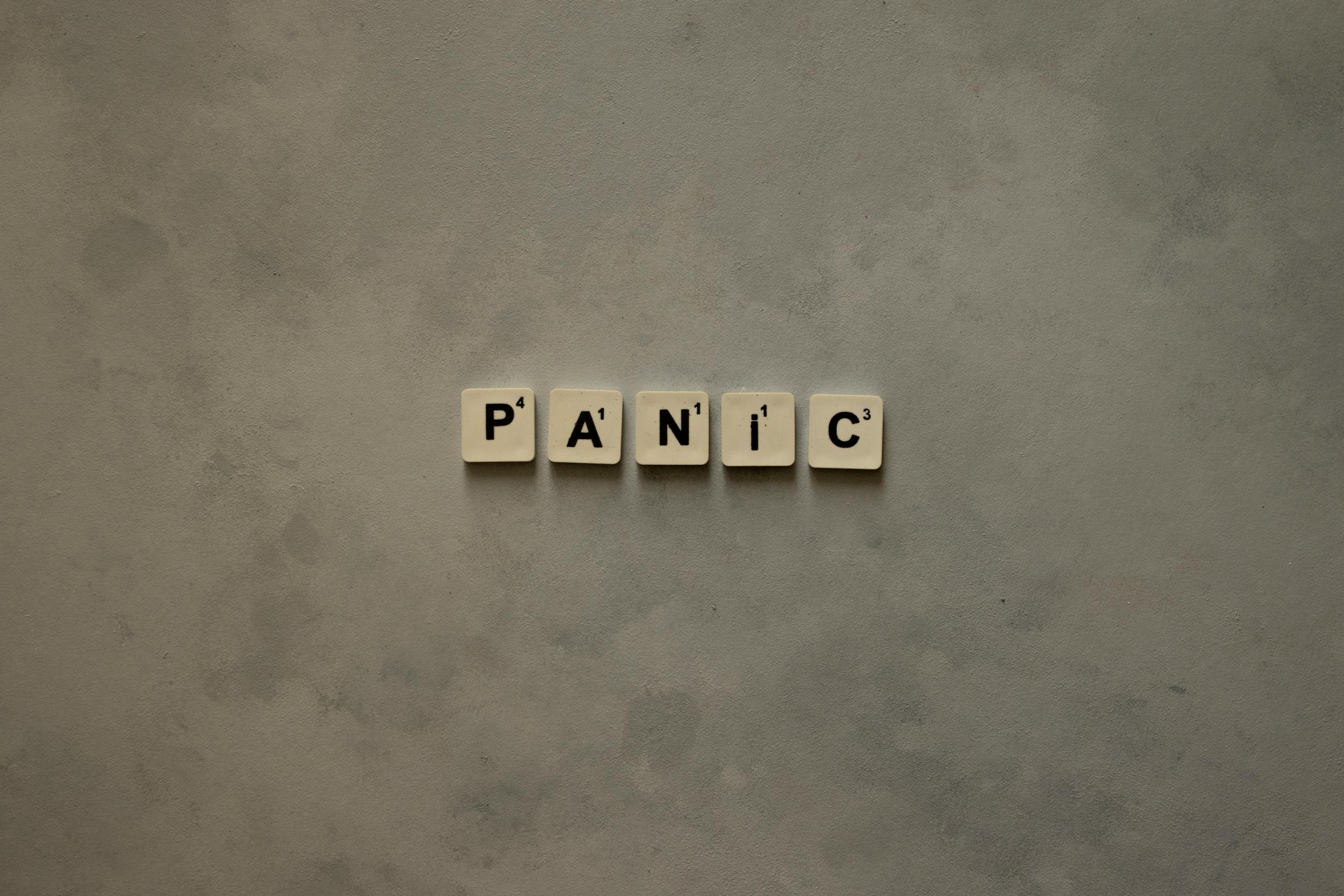 Scrabble tiles forming the word 'Panic' on a simple neutral background, symbolizing anxiety.