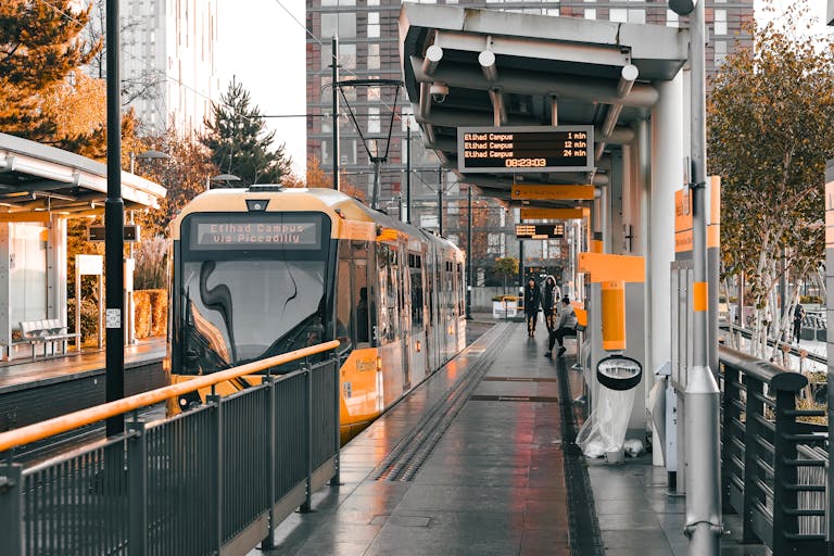 Tram at Salford Quays station showcasing urban architecture and sunset warmth.