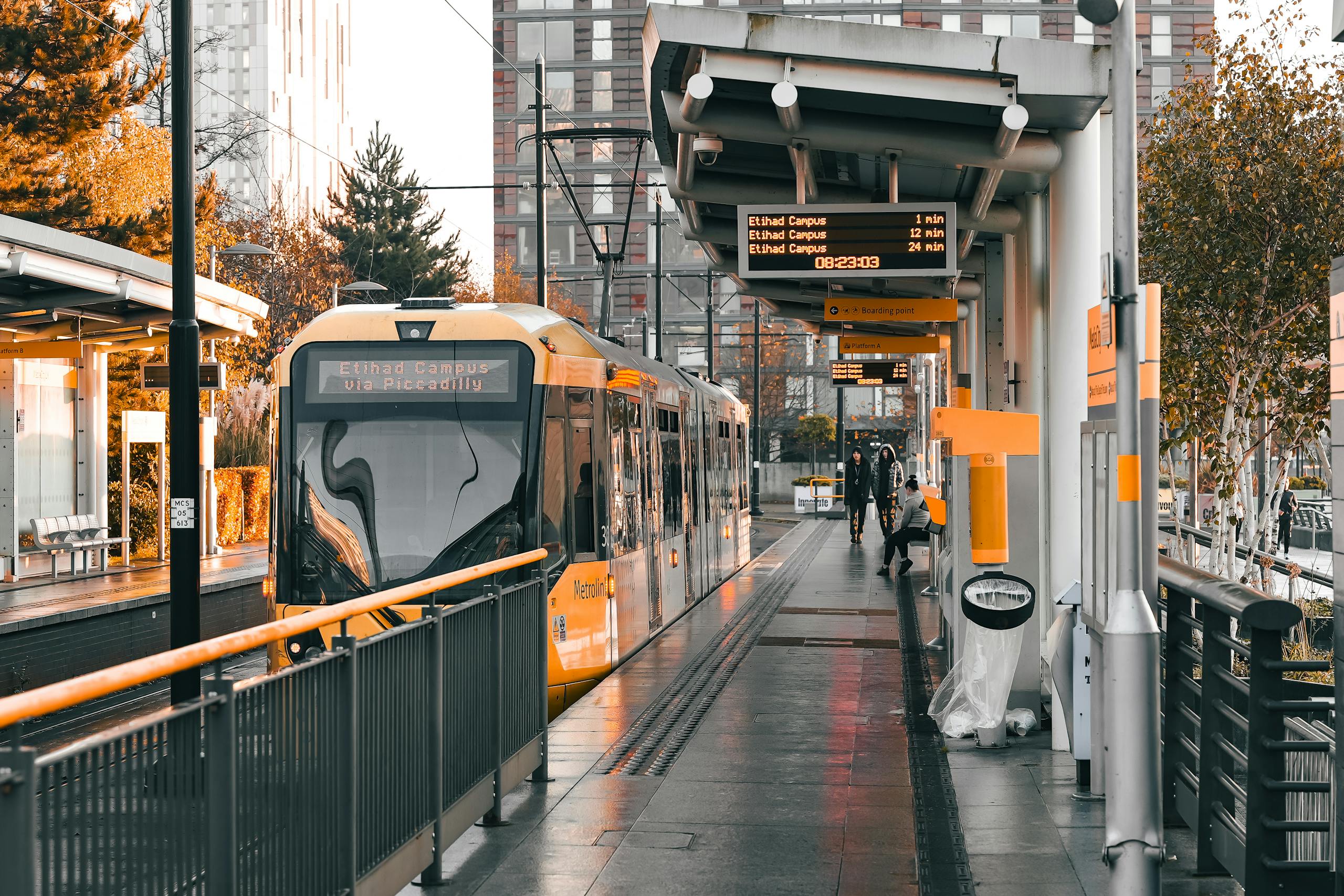 Tram at Salford Quays station showcasing urban architecture and sunset warmth.