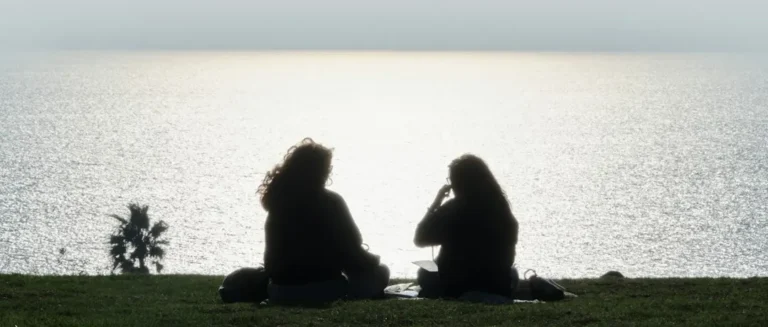 Two people sat talking looking out at the sea