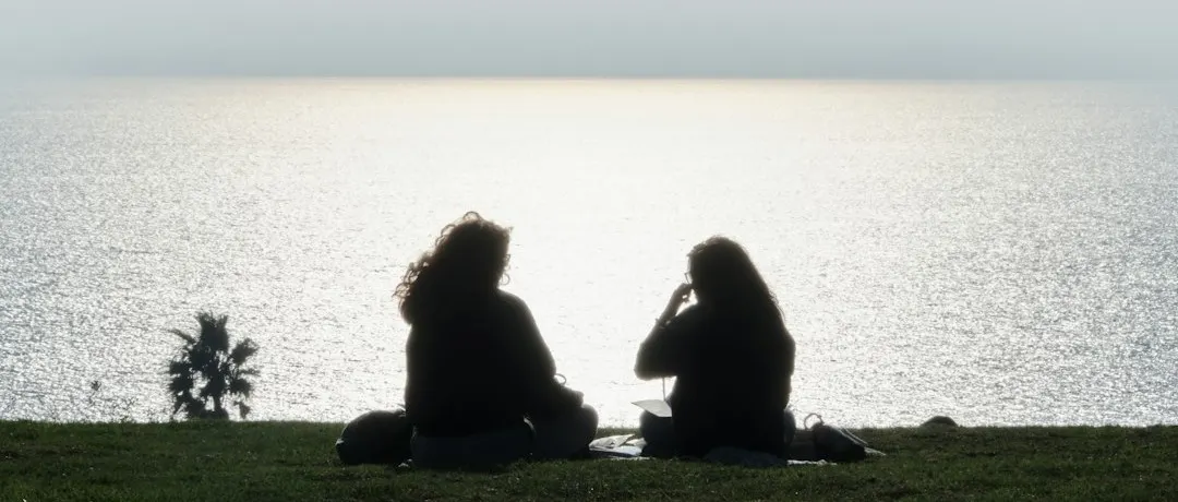 Two people sat talking looking out at the sea